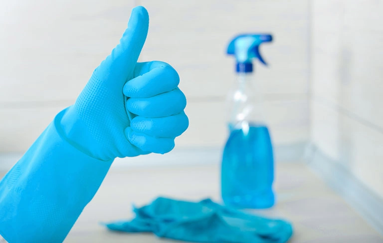 Dłoń w rękawiczce oraz niebieski płyn